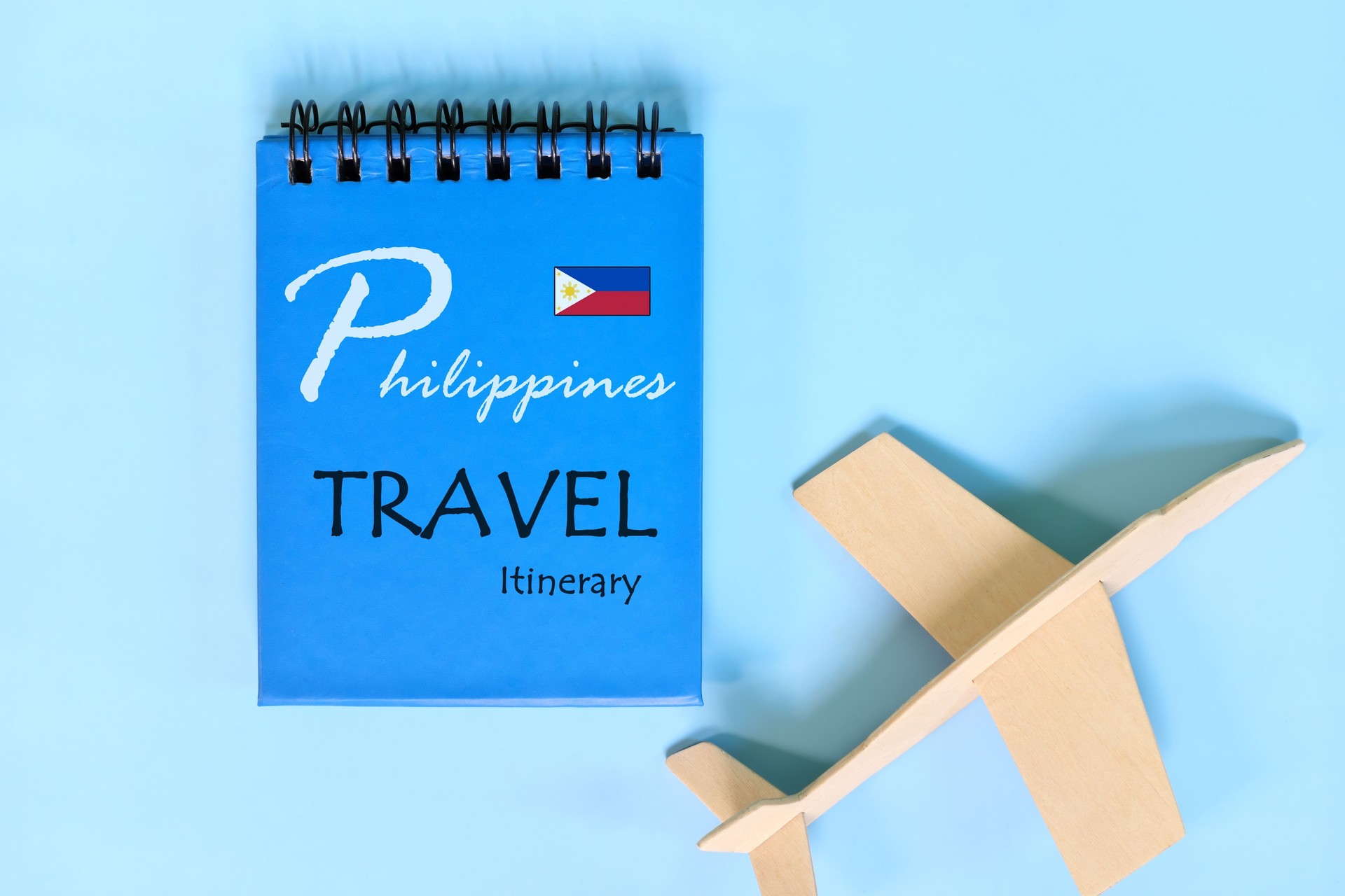 Philippines travel plan or itinerary written on blue notepad with flag and wooden airplane. Tour guide and outline.