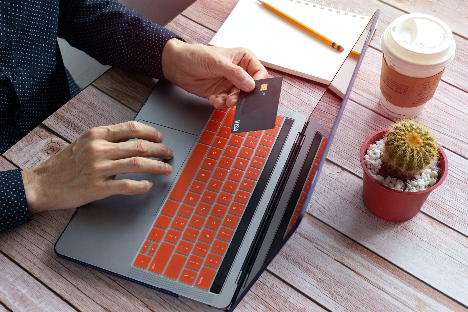 Close up of hands holding black credit card and typing on laptop keyboard. Online banking or payment concept